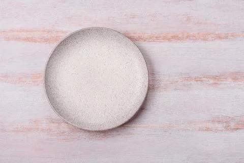 An empty round ceramic plate on a dark, textured white background. An empty.. Stock Photos