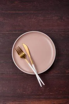 An empty round ceramic plate on a dark, textured brown background. An empty.. Stock Photos
