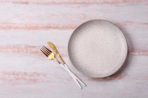 An empty round ceramic plate on a dark, textured white background. An empty.. Stock Photos