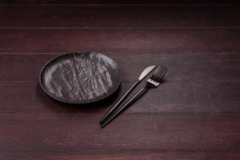 An empty round ceramic plate on a dark, textured brown background. An empty.. Stock Photos
