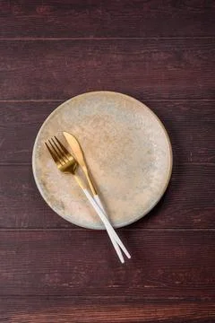 An empty round ceramic plate on a dark, textured brown background. An empty.. Stock Photos
