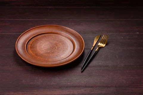 An empty round ceramic plate on a dark, textured brown background. An empty.. Stock Photos