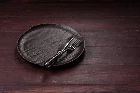 An empty round ceramic plate on a dark, textured brown background. An empty r Stock Photos