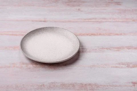An empty round ceramic plate on a dark, textured white background. An empty.. Stock Photos
