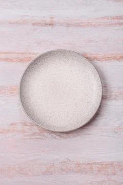 An empty round ceramic plate on a dark, textured white background. An empty.. Stock Photos