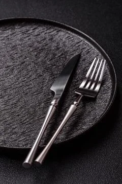 An empty round ceramic plate, knife, and fork as a dining table setting. An.. Stock Photos