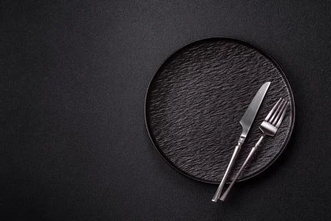 An empty round ceramic plate, knife, and fork as a dining table setting. An.. Stock Photos