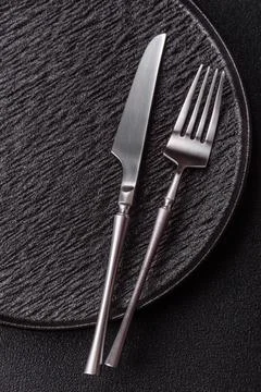 An empty round ceramic plate, knife, and fork as a dining table setting. An.. Stock Photos