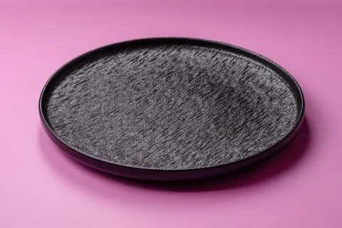 An empty round ceramic plate on a pink background as a kitchen utensil. An .. Stock Photos