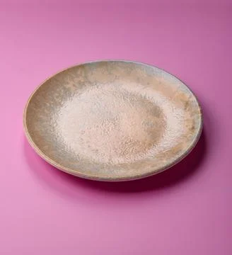 An empty round ceramic plate on a pink background as a kitchen utensil. An .. Stock Photos
