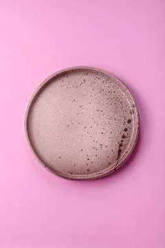 An empty round ceramic plate on a pink background as a kitchen utensil. An .. Stock Photos