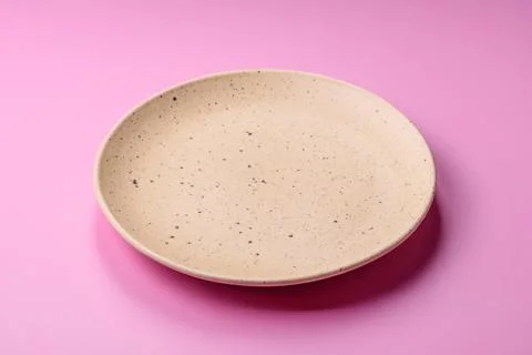 An empty round ceramic plate on a pink background as a kitchen utensil. An .. Stock Photos