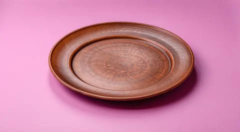 An empty round ceramic plate on a pink background as a kitchen utensil. An .. Stock Photos