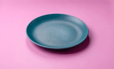 An empty round ceramic plate on a pink background as a kitchen utensil. An .. Stock Photos