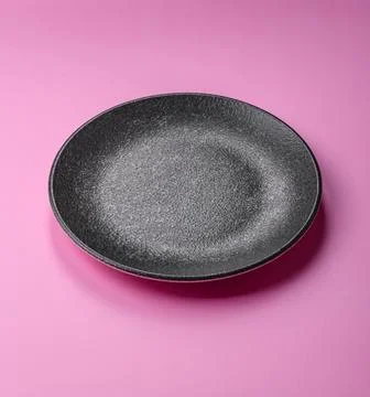 An empty round ceramic plate on a pink background as a kitchen utensil. An .. Stock Photos