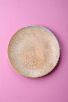 An empty round ceramic plate on a pink background as a kitchen utensil. An .. Stock Photos