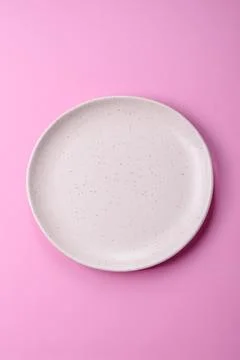An empty round ceramic plate on a pink background as a kitchen utensil. An .. Stock Photos