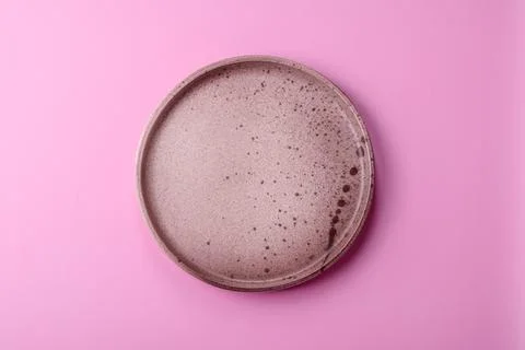 An empty round ceramic plate on a pink background as a kitchen utensil. An .. Stock Photos