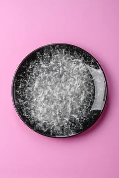 An empty round ceramic plate on a pink background as a kitchen utensil. An .. Stock Photos