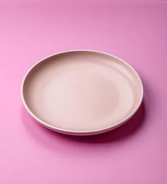 An empty round ceramic plate on a pink background as a kitchen utensil. An .. Stock Photos