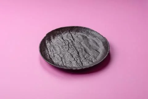 An empty round ceramic plate on a pink background as a kitchen utensil. An .. Stock Photos