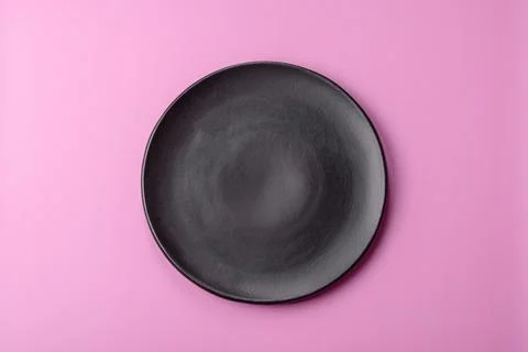 An empty round ceramic plate on a pink background as a kitchen utensil. An .. Stock Photos