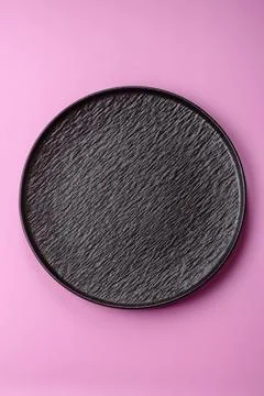 An empty round ceramic plate on a pink background as a kitchen utensil. An .. Stock Photos