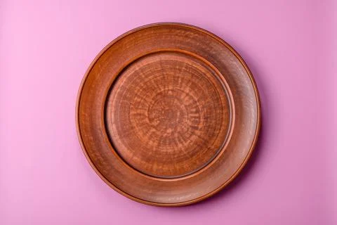 An empty round ceramic plate on a pink background as a kitchen utensil. An .. Stock Photos