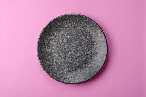 An empty round ceramic plate on a pink background as a kitchen utensil. An .. Stock Photos