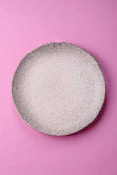 An empty round ceramic plate on a pink background as a kitchen utensil. An .. Stock Photos