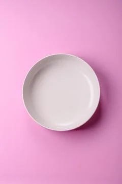 An empty round ceramic plate on a pink background as a kitchen utensil. An .. Stock Photos