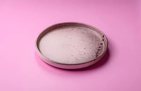 An empty round ceramic plate on a pink background as a kitchen utensil. An .. Stock Photos