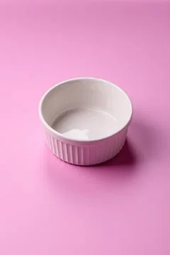 An empty round ceramic plate on a pink background as a kitchen utensil. An .. Stock Photos