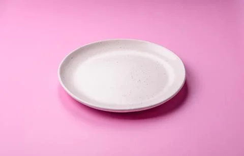An empty round ceramic plate on a pink background as a kitchen utensil. An .. Stock Photos