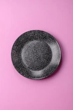 An empty round ceramic plate on a pink background as a kitchen utensil. An .. Stock Photos