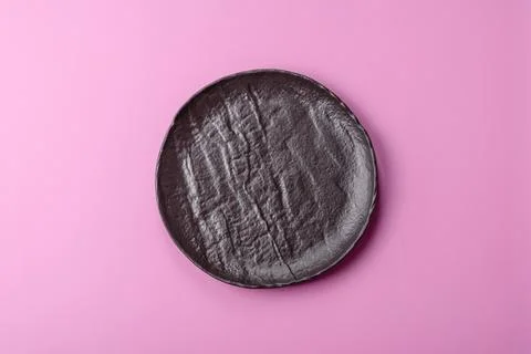 An empty round ceramic plate on a pink background as a kitchen utensil. An .. Stock Photos
