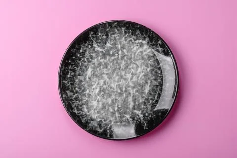 An empty round ceramic plate on a pink background as a kitchen utensil. An .. Stock Photos