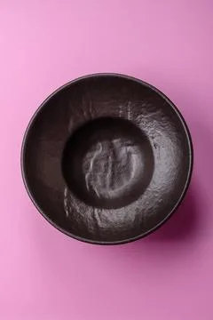 An empty round ceramic plate on a pink background as a kitchen utensil. An .. Stock Photos