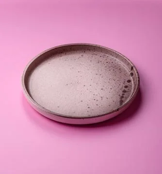 An empty round ceramic plate on a pink background as a kitchen utensil. An .. Stock Photos