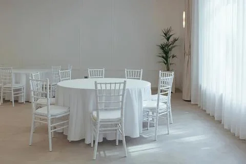 Empty round dining table with white chairs in bright room Stock Photos