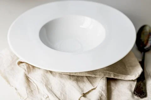 Empty round large ceramic white plate on a gray linen napkin. Selective focus Stock Photos