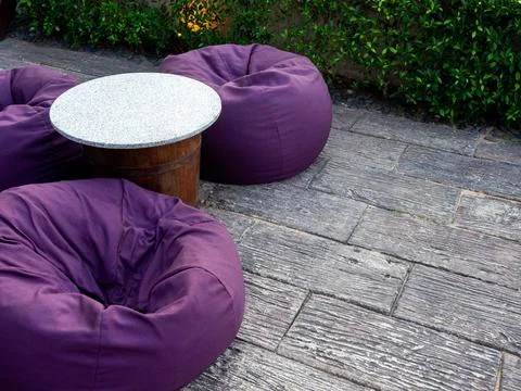 Empty round marble top table with three purple bean bags with copy space on t Foto stock