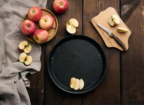 Empty round non-stick baking sheet, fresh apples on a wooden brown table Stock Photos