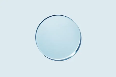Empty round petri dish or glass slide on blue background. Mockup for cosmetic or Stock Photos