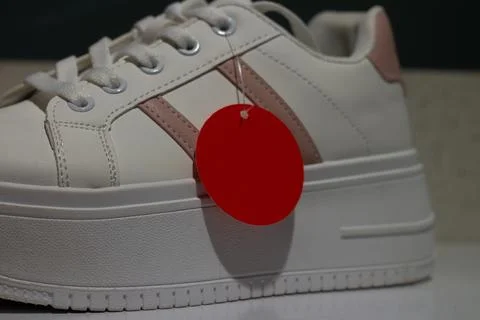 Empty round red tag with copy space for text on white sport sneakers Stock Photos