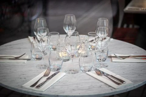Empty round restaurant table with wine glasses and candles Stock Photos