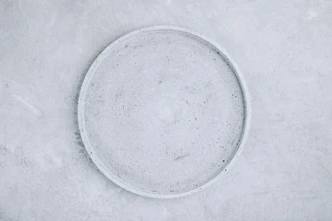 Empty round stone plate on gray concrete background, top view Stock Photos