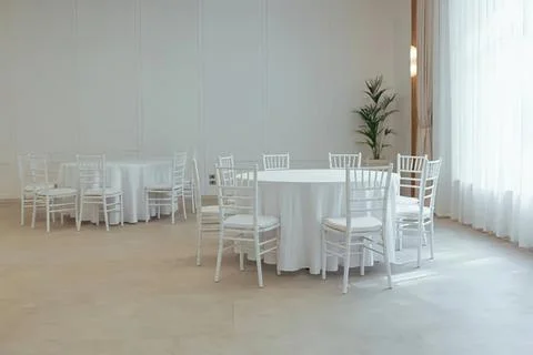 Empty round tables with white chairs in bright room Stock Photos