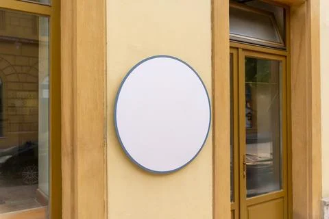 Empty round wall sign mounted beside a storefront entrance, ideal for logo .. Fotos de archivo