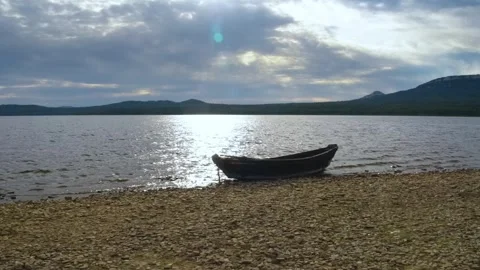Empty Rowboat on a Rocky Shore of a Large Mountain Lake in the Southern Urals, R Stock Footage 325349189